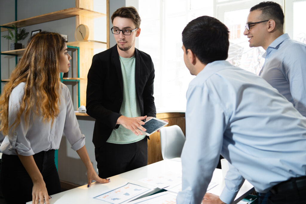 Four colleagues discussing documents around an office table